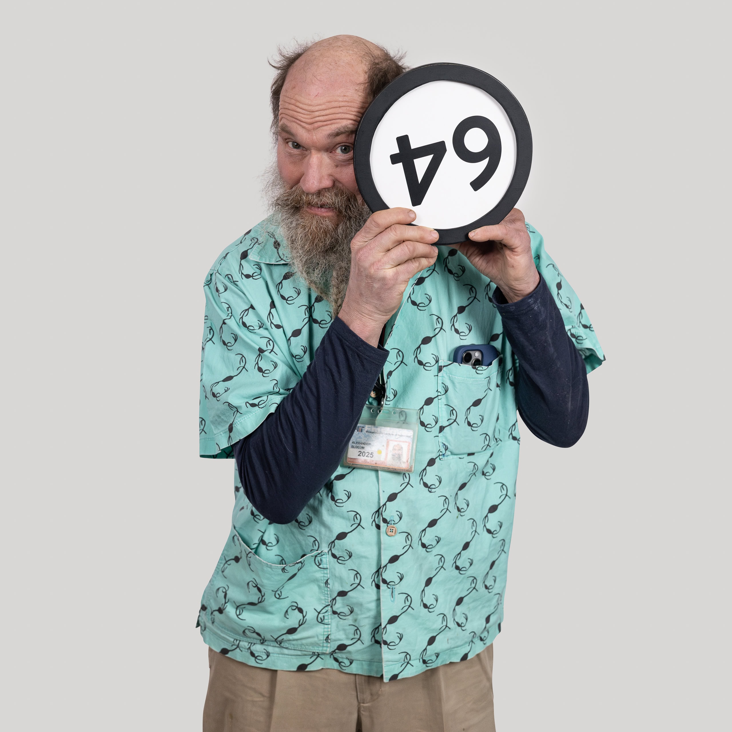 64-year-old man holds the number 64 in the 1 to Infinity, MIT portrait series by Danny Goldfield.