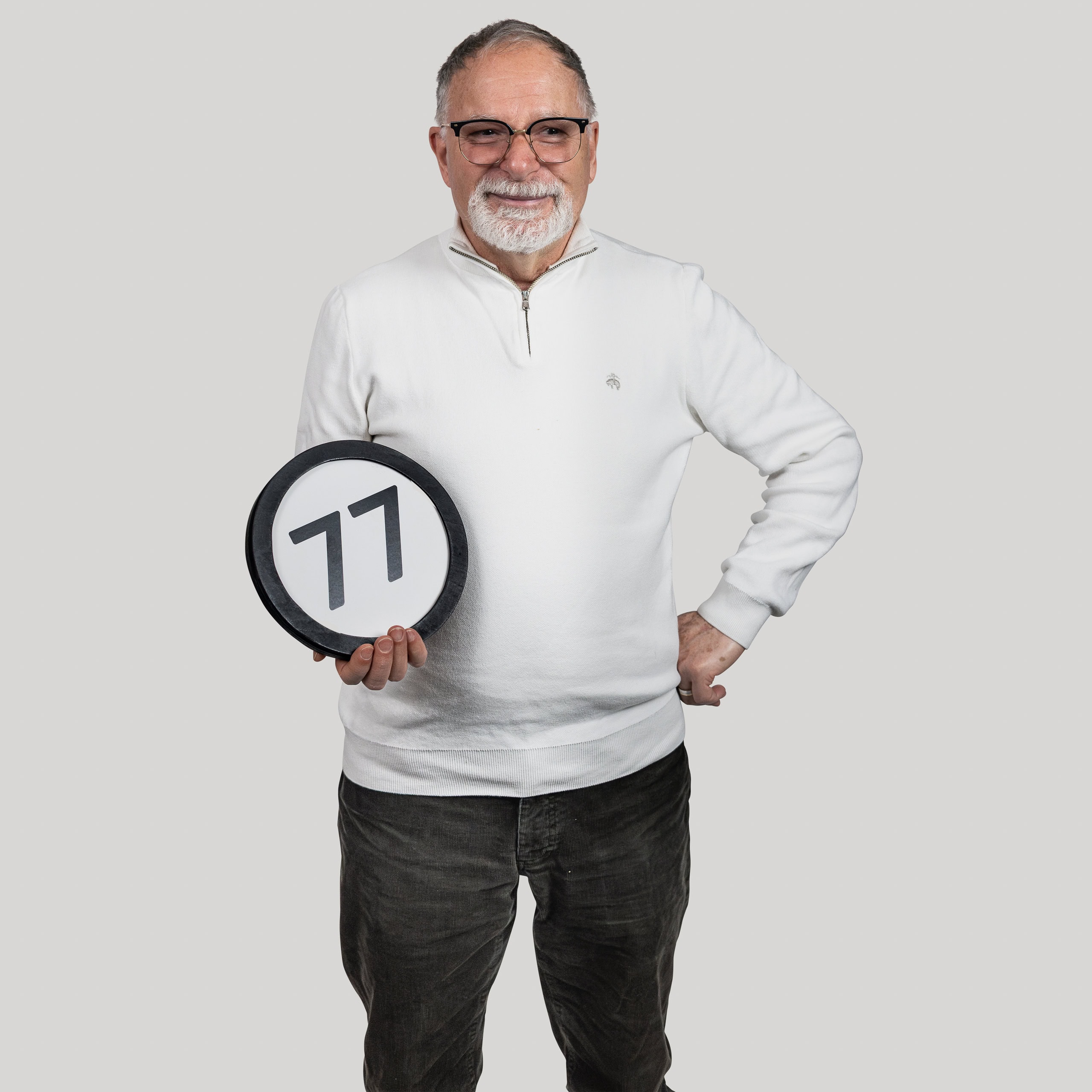77-year-old man holds the number 77 in the 1 to Infinity, MIT portrait series by Danny Goldfield.