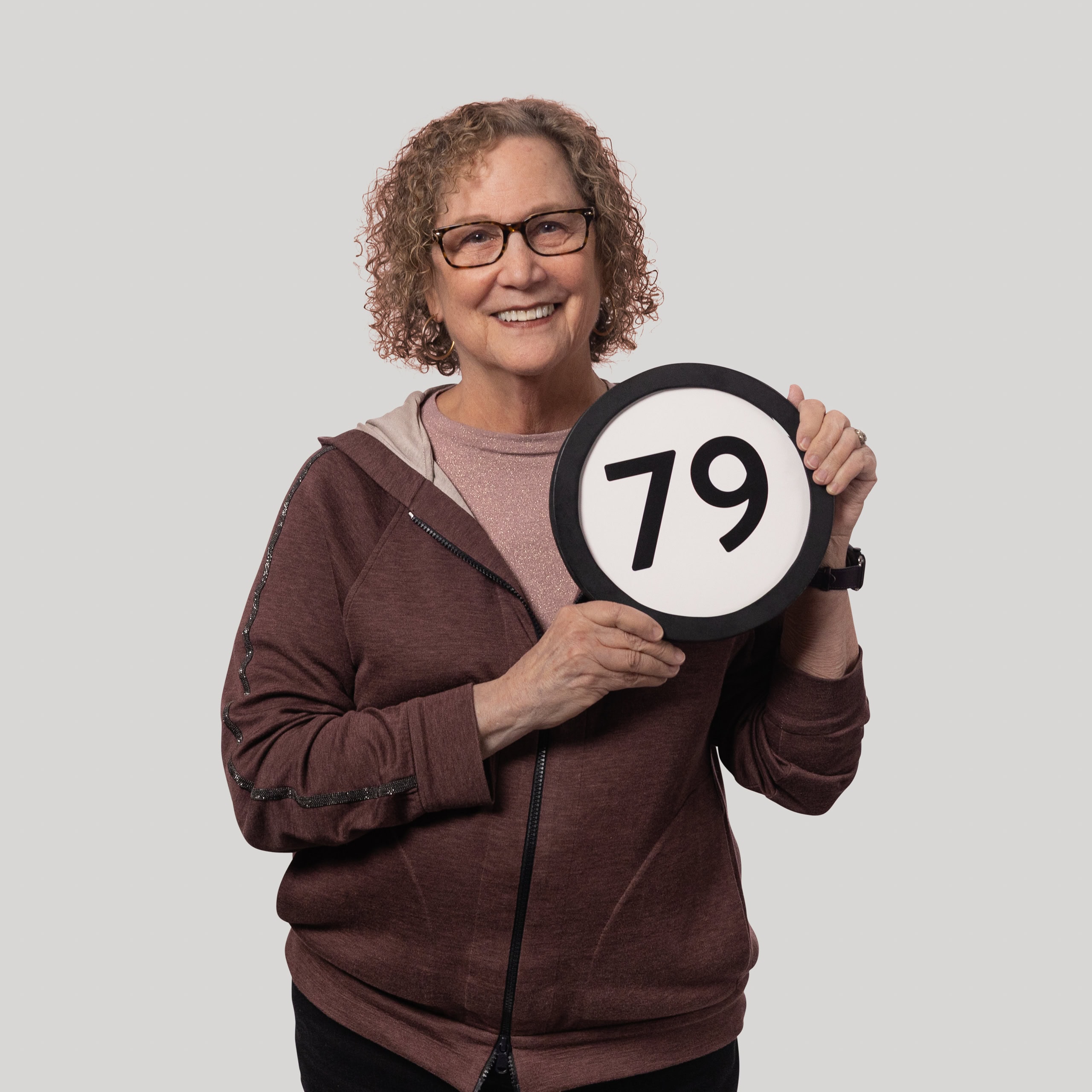 79-year-old woman holds the number 79 in the 1 to Infinity, MIT portrait series by Danny Goldfield.